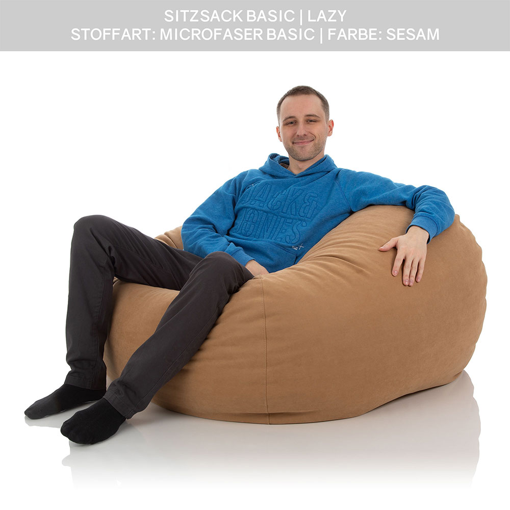 Ein junger Mann versinkt bequem in einen XXL Sitzsack Lazy der Farbe Sesam