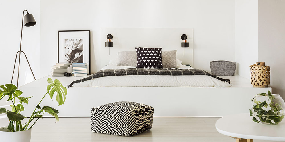 Ein rechteckiges Pouf-Bodenkissen mit schwarz-weißem Muster in einem Schlafzimmer
